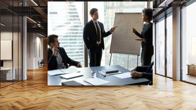 Two young mixed race speakers in formal wear standing near whiteboard, presenting corporate marketing strategy to focused ceo executive managers at brainstorming meeting or educational workshop. Wall mural