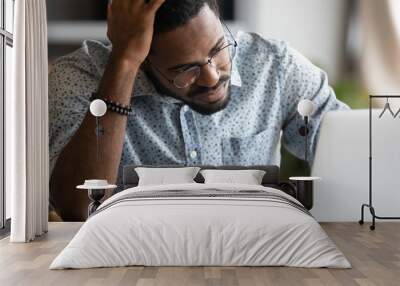 Unhappy tired african American male employee working on laptop look at screen lack motivation or inspiration, unmotivated frustrated biracial man read bad negative news on computer at workplace Wall mural