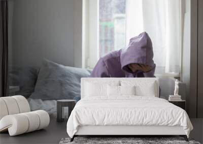 Unhappy young adolescent 12s kid girl sitting on comfortable bed, feeling exhausted or depressed alone at home. Stressed teen child suffering from headache or having psychological mental problems. Wall mural