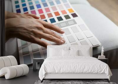 Unrecognizable female hands on paint swatches palette close up. Fashion designer woman use pantone samples choose color prepares for coming repairs works selecting wall colour, home renovation concept Wall mural