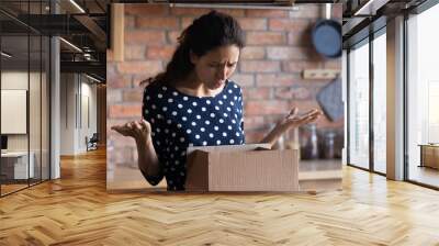 Wasted money. Irritated latin woman courier service client receive broken damaged goods in delivery box. Angry young lady get wrong order in parcel from online shop disappointed with product quality Wall mural