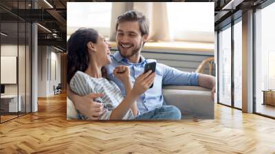 Wide banner panoramic view of overjoyed millennial couple celebrate online win on cellphone together. Happy young Caucasian man and woman triumph with good sale deal or promotion discount on cell. Wall mural