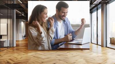 Wonderful thing. Excited young couple husband and wife sitting at home office by pc screen screaming in delight receiving good news profitable offer, getting message email of loan mortgage approval Wall mural