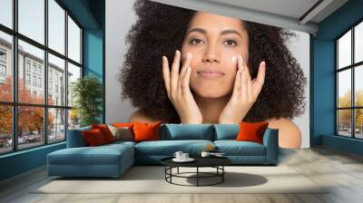 Young african american woman applying professional skincare product. Wall mural