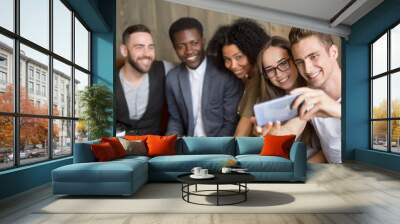 Young caucasian man making selfie on smartphone at meeting with multiracial millennial friends, diverse happy people having fun in cafe together taking group self-portrait photo on mobile phone Wall mural