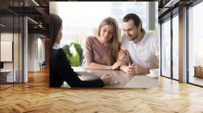 Young couple came to real estate agency to consult an expert, family ready to buy rent flat, considering bank loan for apartment purchase, taking mortgage credit, choosing place to live Wall mural