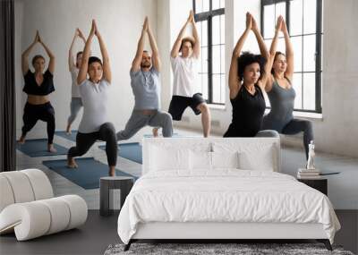 Young diverse people doing Warrior one exercise, practicing yoga Wall mural