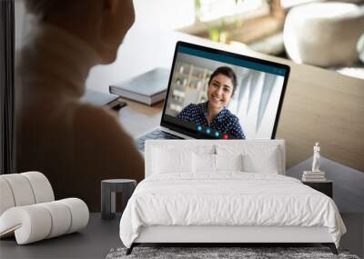 Young female sit at desk at home talk on video call with Indian colleague, woman have pleasant Webcam conference with biracial coworker, communicate online using wireless Internet connection Wall mural