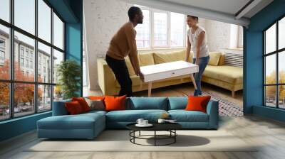 Young happy african american couple moving wooden table. Attractive family of diverse woman and man relocation furniture in new flat. Husband and wife perform permutation. First time buyers Wall mural