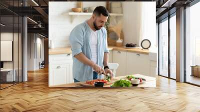 Young man stand in kitchen cooking salad for lunch Wall mural