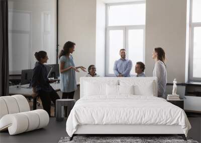 Young multiethnic business team brainstorming in project, sharing creative ideas for startup on meeting in office, sitting, standing in circle, talking, smiling, laughing Wall mural