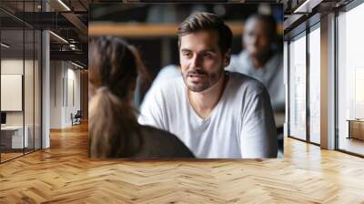 Young serious man having conversation with woman girlfriend in cafe Wall mural