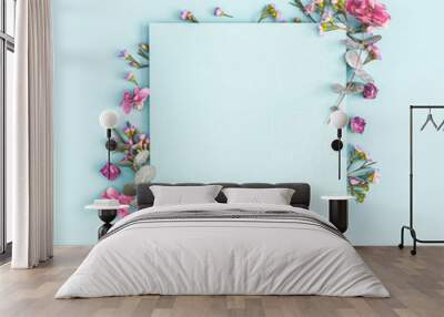 Flowers composition. Paper blank, pink flowers on pastel blue background. Flat lay, top view, copy space, square Wall mural