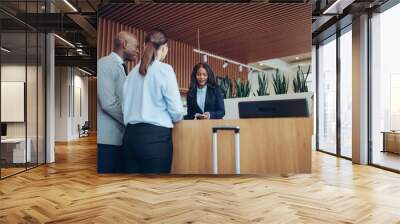 African American concierge checking in two smiling hotel guests Wall mural