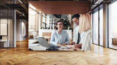 Businesspeople laughing while working at an office table Wall mural