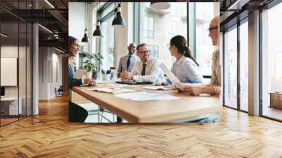 Diverse businesspeople laughing during a meeting around an offic Wall mural