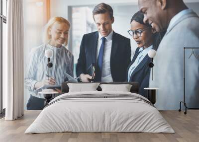 Diverse businesspeople smiling while using a laptop in an office Wall mural