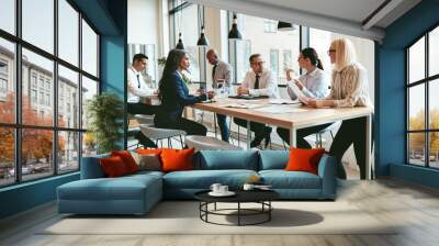 Diverse group of businesspeople talking together around an offic Wall mural