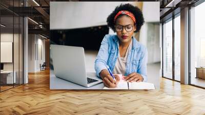 focused young african female entrepreneur writing down business Wall mural