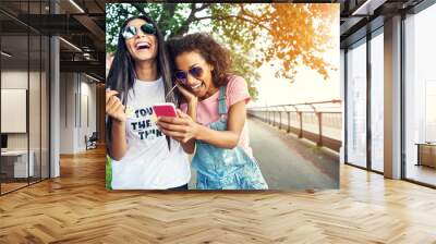 Giddy female friends falling over one another Wall mural