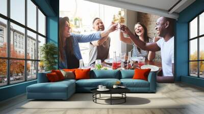 Group of four laughing adults toasting drinks Wall mural