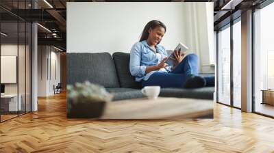 laughing african woman sitting at home using a digital tablet Wall mural