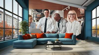 Laughing group of diverse businesspeople working around an offic Wall mural