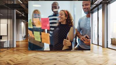 Laughing team of designers brainstorming together in an office Wall mural