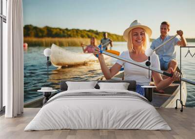 Laughing young woman canoeing with friends on a sunny afternoon Wall mural