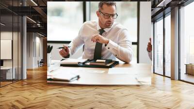 Mature businessman going over paperwork during a boardroom meeti Wall mural