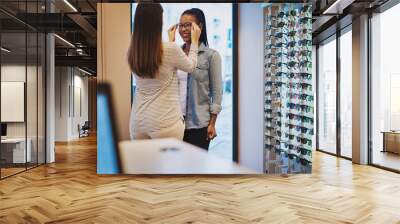 Optometrist helping a young woman in her store Wall mural