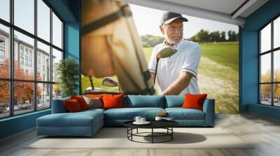 Senior man preparing to play golf on a sunny day Wall mural