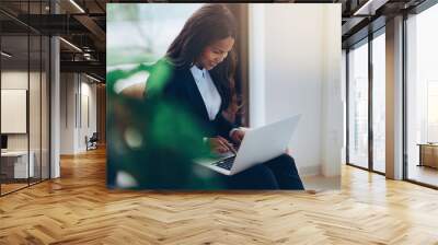 Smiling African American businesswoman using a laptop in an offi Wall mural