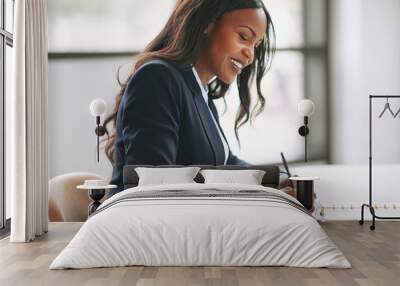 Smiling African American businesswoman writing notes in her day Wall mural