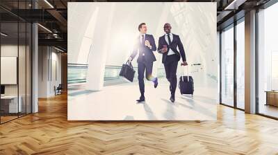 Smiling businessmen running to catch a flight in an airport Wall mural