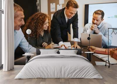 Smiling businesspeople discussing paperwork together in an offic Wall mural