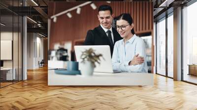 Smiling businesspeople standing in an office working on a laptop Wall mural