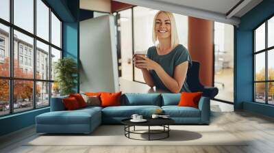 smiling businesswoman drinking coffee while working in an office Wall mural