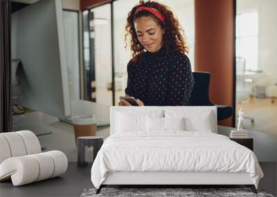 Smiling businesswoman reading a text message at her office desk Wall mural