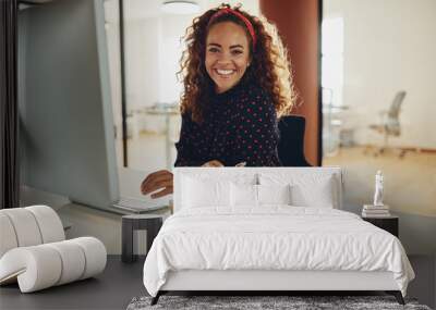 smiling businesswoman sitting at her office workstation going ov Wall mural