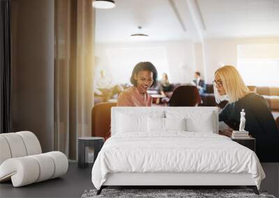 Smiling businesswomen discussing work on a laptop in an office Wall mural