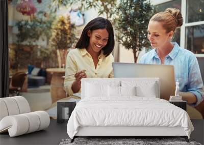 Smiling businesswomen using a laptop in an office lounge Wall mural