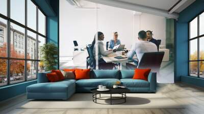 Smiling coworkers meeting together inside of a glass walled offi Wall mural