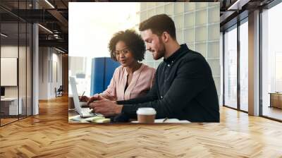 Smiling coworkers using a laptop together in an office Wall mural