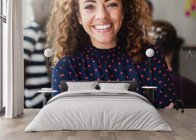 Smiling designer in an office with colleagues in the background Wall mural