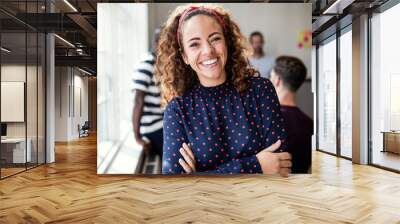 Smiling female designer standing in an modern office Wall mural