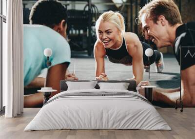 Smiling friends planking together during a gym workout session Wall mural