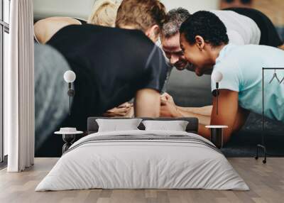 Smiling friends planking together on a gym floor Wall mural