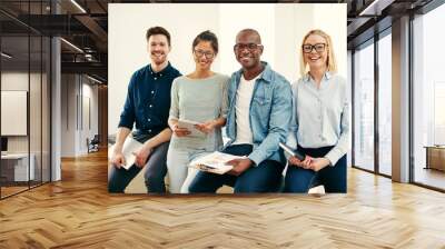 Smiling group of young businesspeople sitting on an office table Wall mural