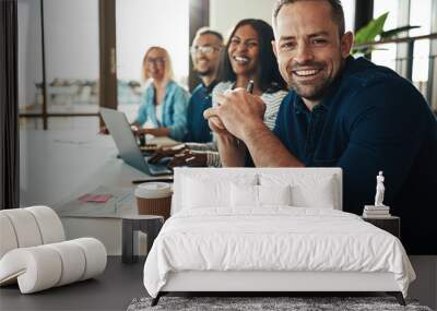 Smiling mature businessman sitting with colleagues in an office Wall mural